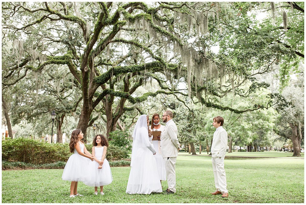 forsyth park destination elopement under oak trees with children all dressed in white