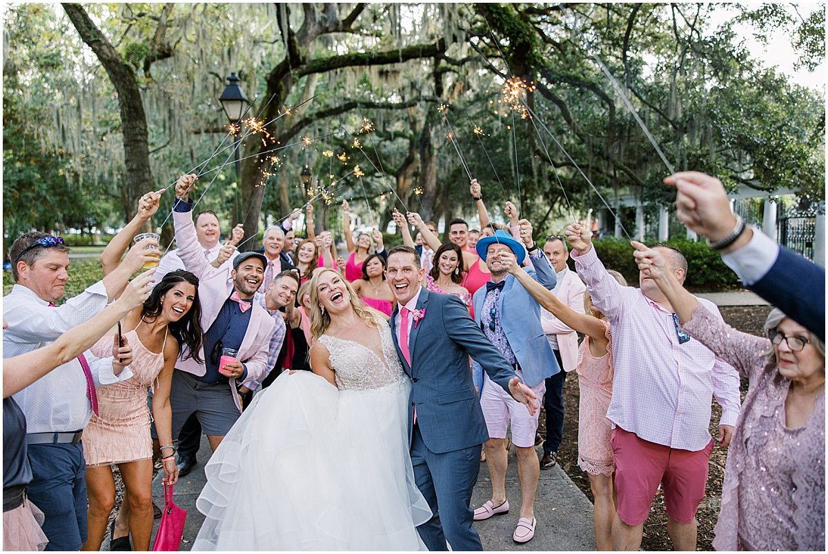 bride and groom posing with their guests after sparkler exit in forsyth park by savannah wedding photographer amber elizabeth weddings