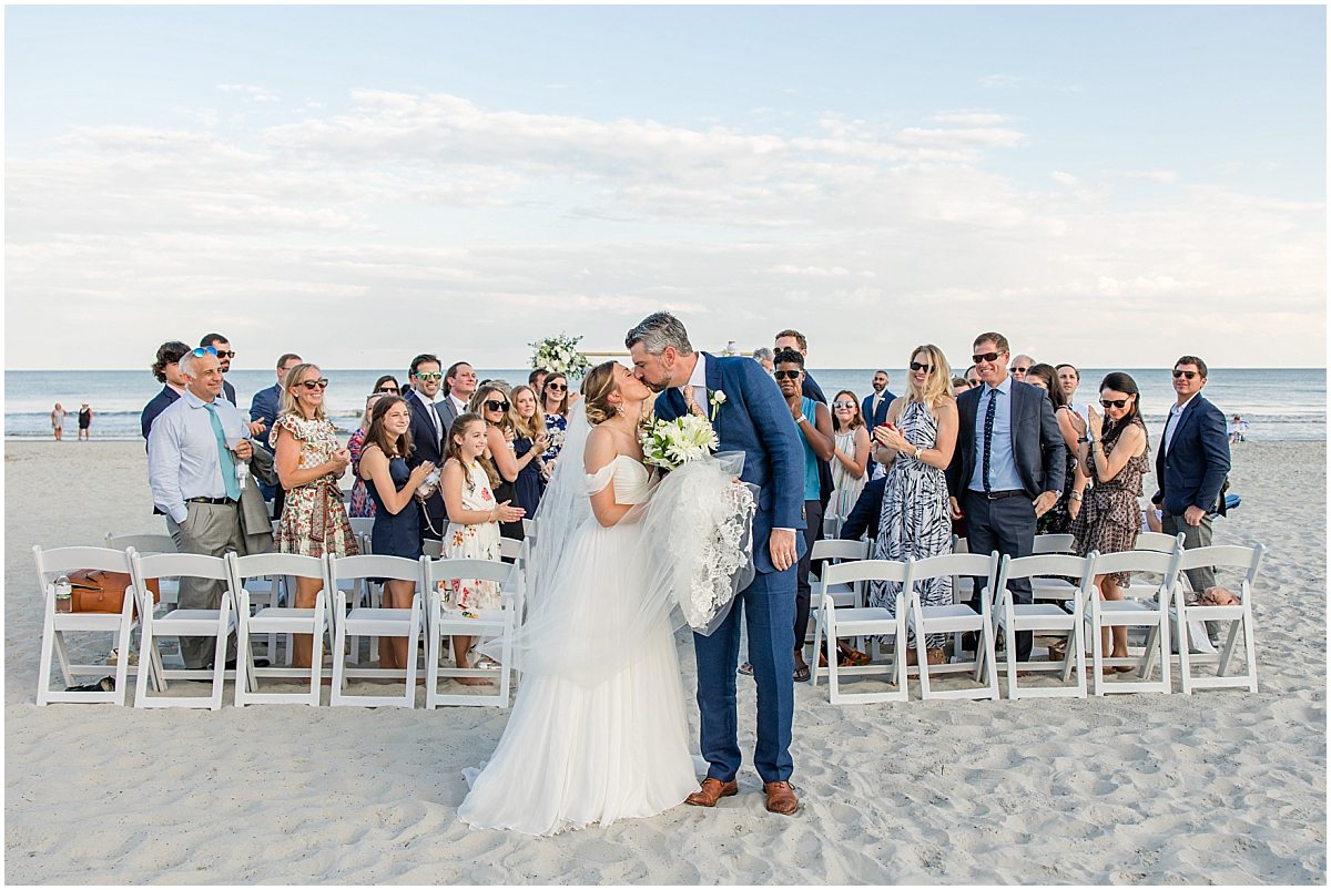couple kissing after they walk down the aisle on the beach